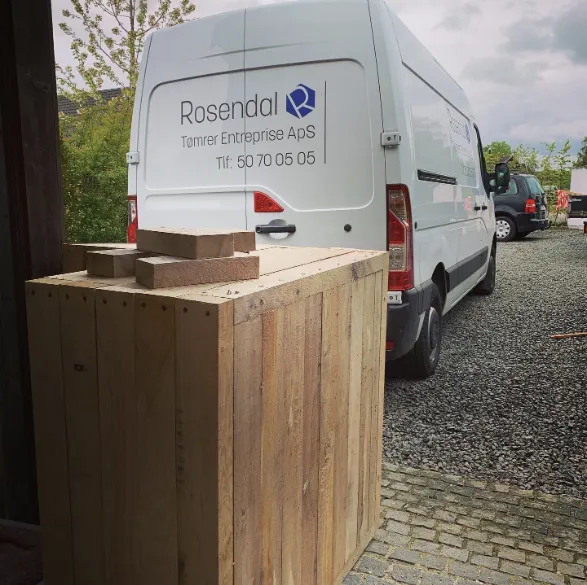 Rosendal Tømrers firmabil ved værkstedet med en kasse i træ
