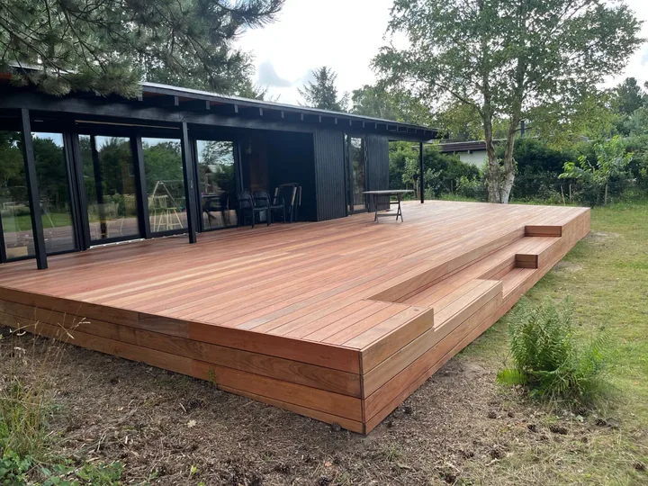 Ny terrasse i jatoba på trækonstruktion med indbyggede trapper ved et sort hus i Liseleje.