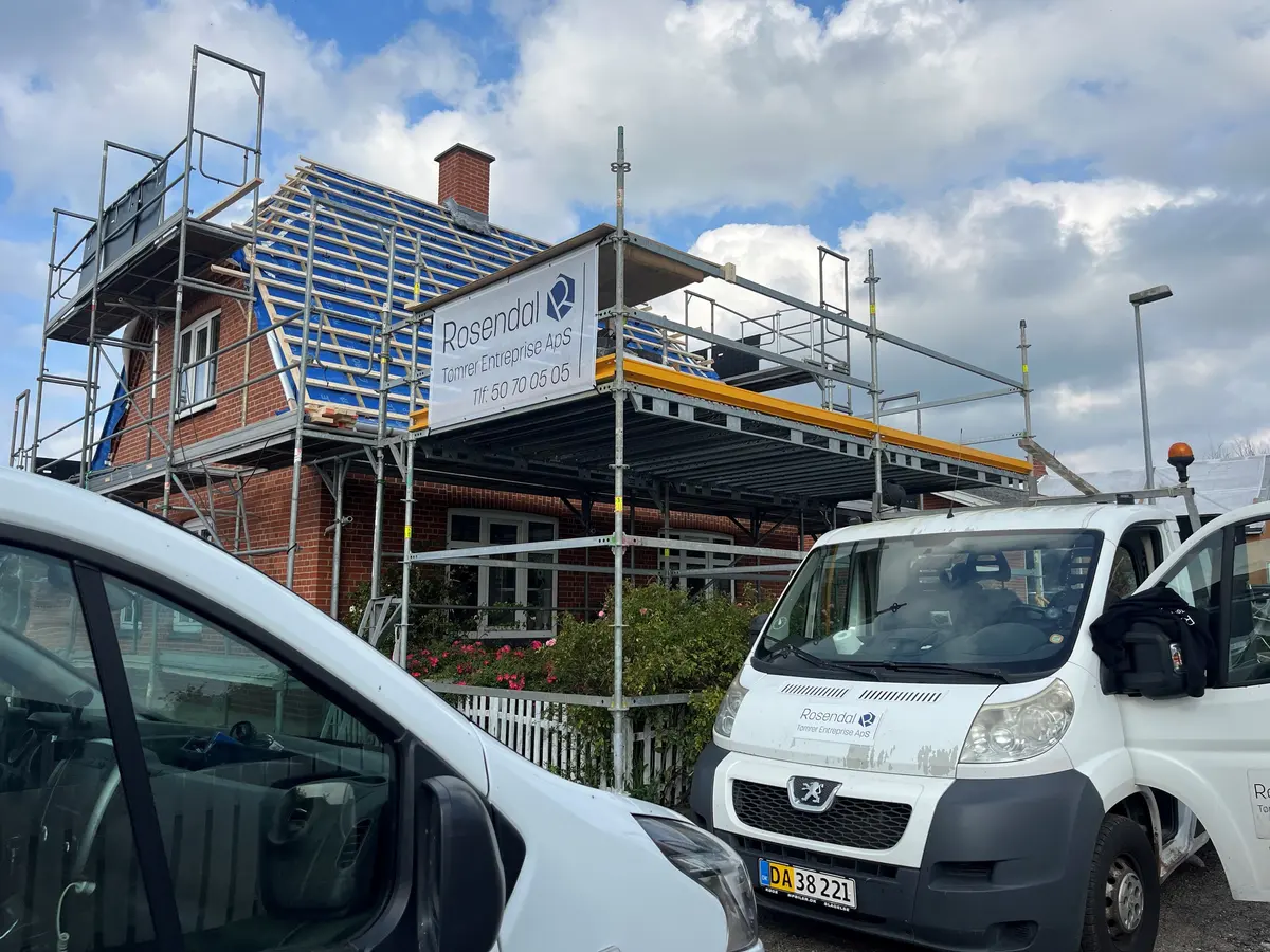 Stillads med Rosendal-banner og firmabiler under udskiftning af et tag